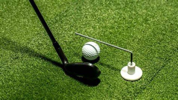 Where should you aim when striking a golf ball?